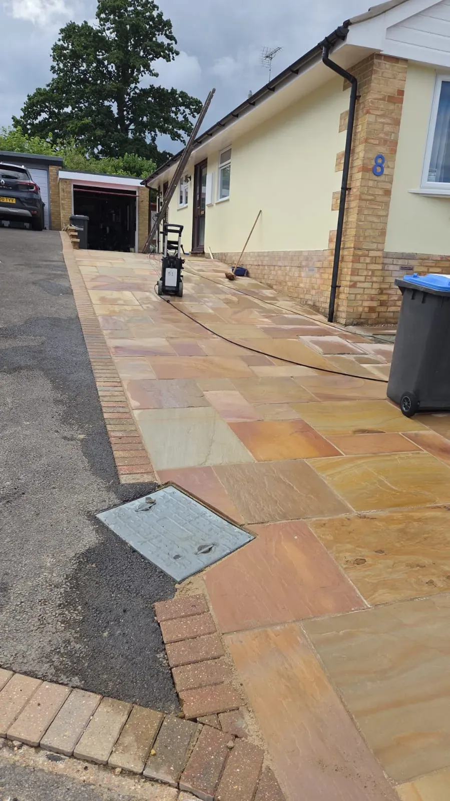 Newly installed Indian sandstone driveway and side path with block paving edging and power washing equipment.